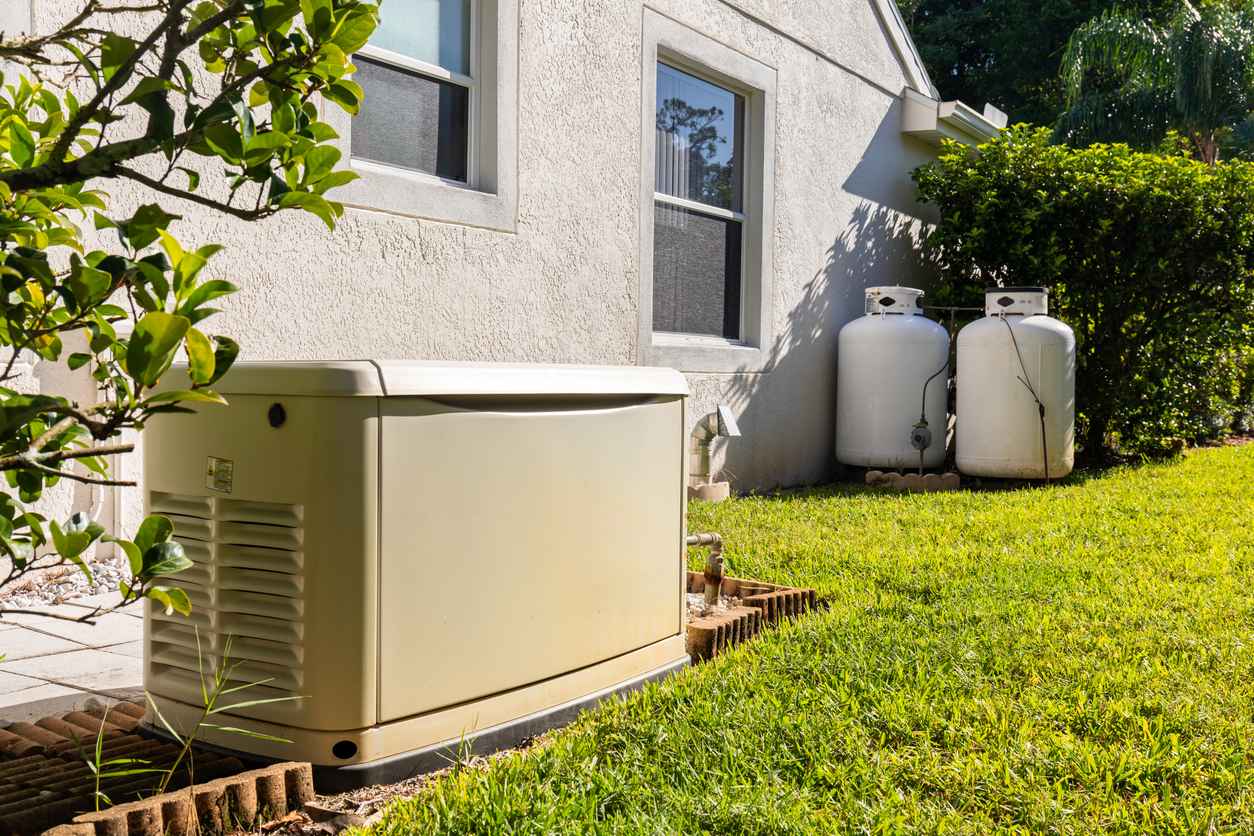 generator and propane tanks in the side yard of a home to provide backup emergency electricity during power outage.